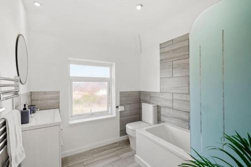 łazienka z wanną, toaletą i oknem w obiekcie Spacious 2 bedroom house with parking & WiFi w mieście Kent