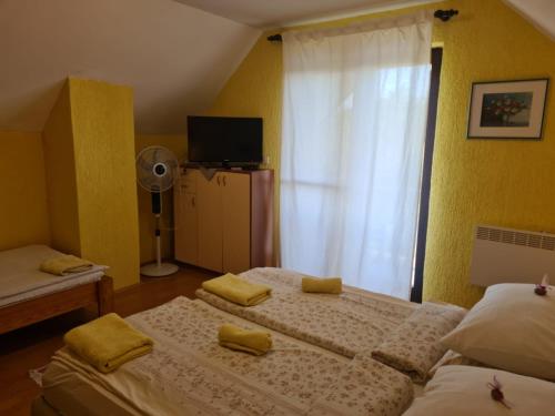a bedroom with two beds and a window with a fan at Croatia Cottage in Nova Kapela