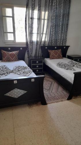 a bedroom with two beds and a window at Appartment Corniche in Sousse