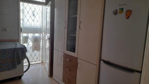 a kitchen with a white refrigerator and a window at Appartment Corniche in Sousse
