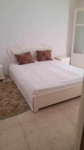 a bedroom with a large white bed with pillows at Appartment Corniche in Sousse