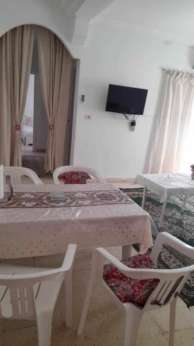 a room with a bed and chairs and a tv at Appartment Corniche in Sousse