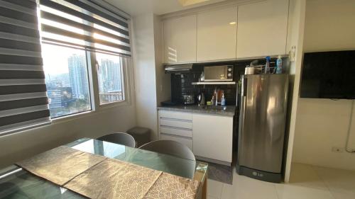 a kitchen with a table and a stainless steel refrigerator at Calyx Residences 18i in Cebu City