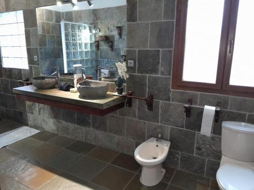 a bathroom with a sink and a toilet and a mirror at La Caze roche Maison d'hôtes in Mahébourg