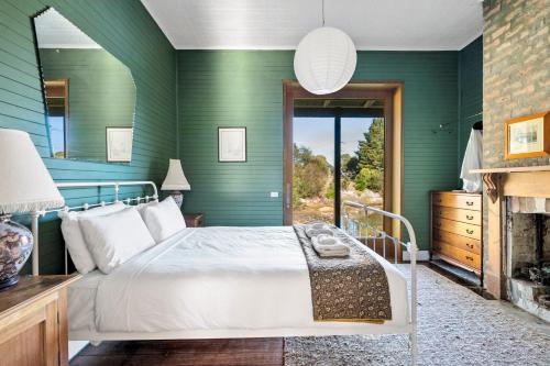 Dormitorio verde con cama y chimenea en 'Questa' Heritage Cottage, en Barnes Bay