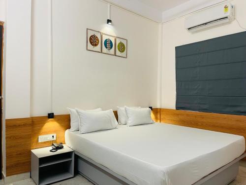 1 dormitorio con 1 cama blanca y una pizarra en la pared en Hotel Insta 18, en Siliguri