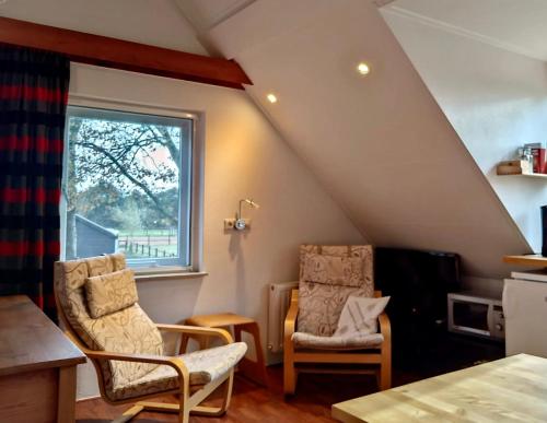 a attic room with two chairs and a window at Appartement Soerte Es in Wapse