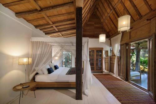 - une chambre avec un lit et un plafond en bois dans l'établissement Villa Maia, à Kerobokan