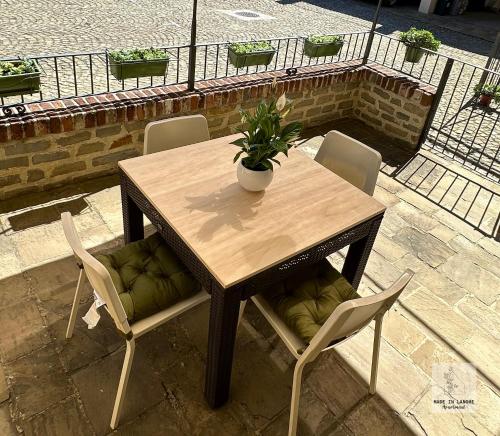 une table en bois avec des chaises et une plante en pot. dans l'établissement Made in Langhe Apartment, à La Morra