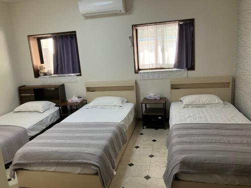 a room with two beds and two windows at 癒しのwonderland 泉 in Gujo