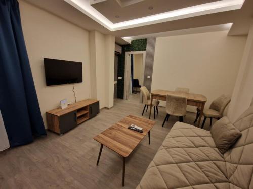 uma sala de estar com um sofá, uma televisão e uma mesa em Square Vanilla Boutique Apart-Hotel em Skopje