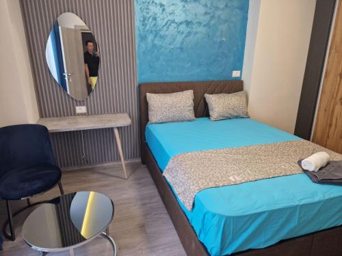 1 dormitorio con cama, espejo y silla en Square Vanilla Boutique Apart-Hotel en Skopie