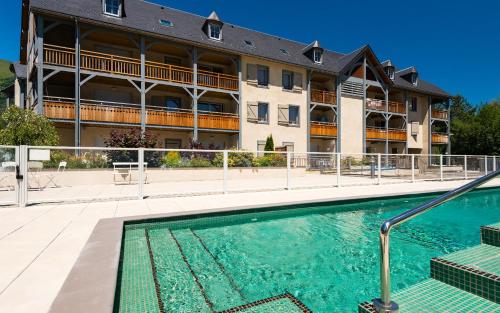 un hôtel avec une piscine devant un immeuble dans l'établissement Lagrange Vacances Le Clos Saint Hilaire, à Saint-Lary-Soulan