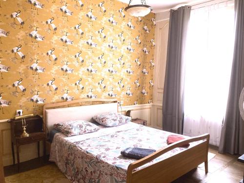 - une chambre avec un lit et du papier peint orné d'oiseaux dans l'établissement La Garconniere Centre Historique Troyes, à Troyes