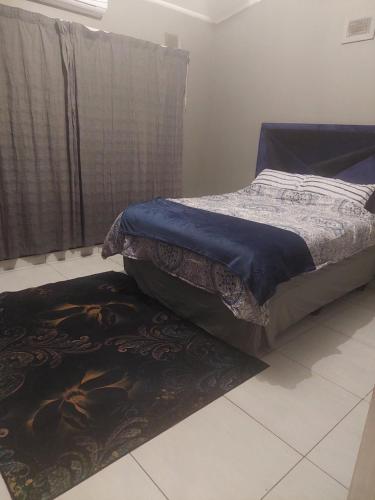 a bedroom with a bed and a rug on the floor at Umtentweni, Seaview Unit Alpero in Port Shepstone