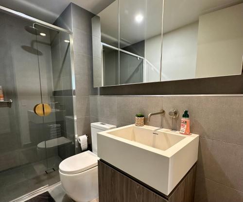 ein Badezimmer mit einem Waschbecken, einem WC und einem Spiegel in der Unterkunft Luxury Top Level 1 Bedroom Apartment with Stunning View in Adelaide CBD - 1 minute walk to Rundle mall - Free Wifi & Netflix in Adelaide
