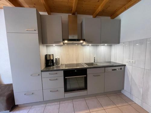 eine Küche mit weißen Schränken und einem Waschbecken in der Unterkunft Ferienwohnung Martin Mathies in Sankt Gallenkirch