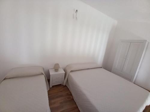 2 Betten in einem kleinen Zimmer mit einem Nachttisch in der Unterkunft Domo Clelia in Nulvi