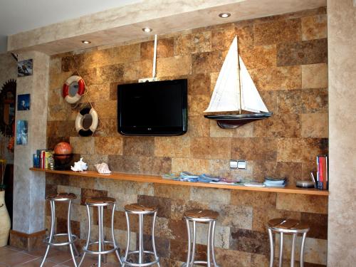 a stone wall with a bar with stools and a tv at Hotel Conde Navío in Sanxenxo