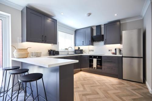 a kitchen with black cabinets and bar stools at Freshly Refurbished Open-plan Dining & Kitchen in Norwich