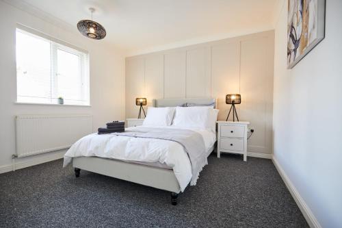 a white bedroom with a bed and two lamps at Elegant Design 75" Smart Tv Long Stay Welcome in Norwich