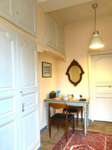 Cette chambre comprend une table avec une chaise et un miroir. dans l'établissement La Garconniere Centre Historique Troyes, à Troyes