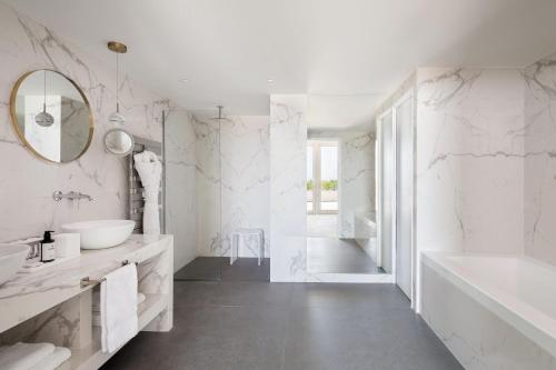 a bathroom with white marble walls and a tub and a sink at JW Marriott Cannes in Cannes