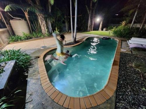 two people in a swimming pool at night at VIVID - House w heated pool, ev station, fireplace in Summerland Point