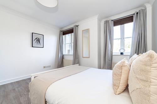 ein weißes Schlafzimmer mit einem großen Bett und Fenstern in der Unterkunft The Brixton Collection in London