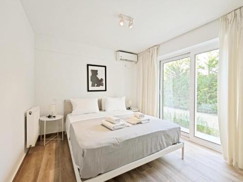 um quarto branco com uma cama e uma grande janela em Kalipsous Apartments by Verde Apartments em Atenas