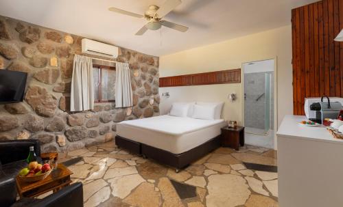 1 dormitorio con cama y pared de piedra en Vered Hagalil Holiday Village Hotel, en Chorazim