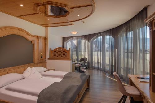 Schlafzimmer mit einem Bett, einem Schreibtisch und Fenstern in der Unterkunft Schönblick - Sport & Active Hotel in Bruneck