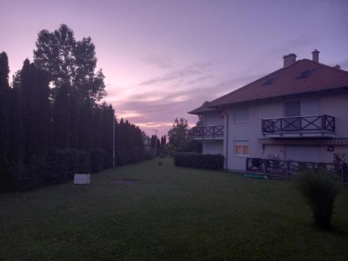 a house in a yard with a sunset in the background at Vadszilva Apartman in Balatonőszöd