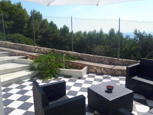 um pátio com 2 cadeiras, uma mesa e uma cerca em Villa Rosa con esclusiva vista sul mare em Corsano