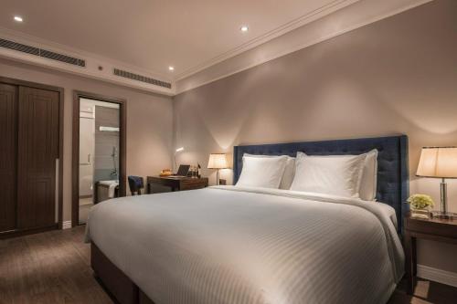 a bedroom with a large white bed with a blue headboard at Luxury Apartment - Rooftop Swimming Pool - Beach Front - Hinata Apartment in Da Nang