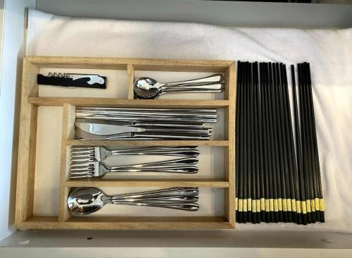 a wooden drawer filled with silver utensils at Luxury Apartment - Rooftop Swimming Pool - Beach Front - Hinata Apartment in Da Nang