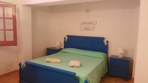 1 dormitorio con 1 cama azul y 2 mesitas de noche en Casetta al mare, en Cefalú