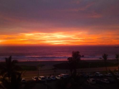 a sunset over the ocean with cars parked at C8 Surfside in Durban