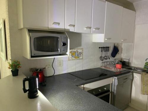 a kitchen with white cabinets and a microwave at C8 Surfside in Durban