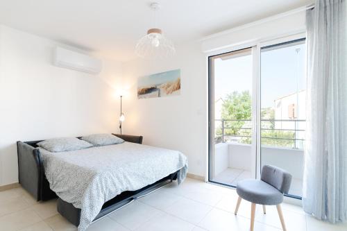 a bedroom with a bed and a chair and a window at Appartement Neuf 4 étoiles - Sunset Lodge, Narbonne Plage in Narbonne