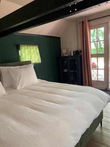 1 cama blanca grande en un dormitorio con una pared verde en Bed and Breakfast Bakrust, met privé sauna Putten, en Putten