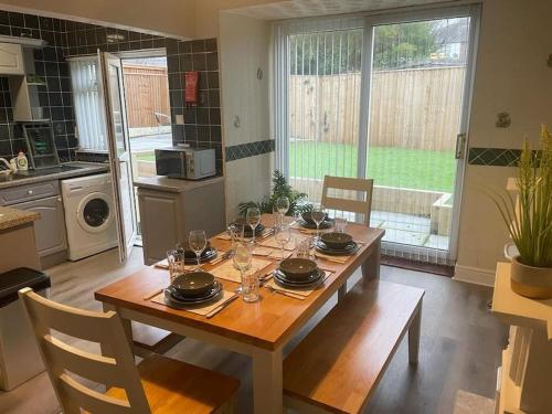 a wooden table with plates and glasses on it in a kitchen at Lovely 3 bedroom house with off street parking in Thornton