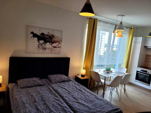 a bedroom with a bed and a table with chairs at Bm Apartamenty w Centrum Szczecin in Szczecin