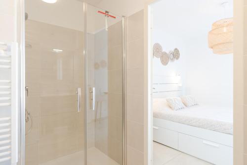 La salle de bains est pourvue d'une douche avec une porte en verre. dans l'établissement Appartement Neuf 4 étoiles - Sunset Lodge, Narbonne Plage, à Narbonne