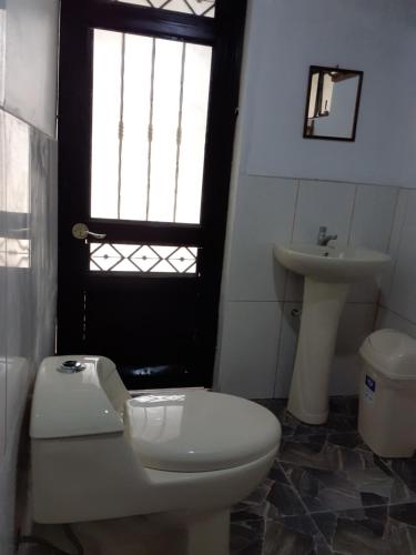 a bathroom with a toilet and a sink and a window at casa montañista lodge & camping in Huaraz