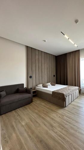 a bedroom with a large bed and a couch at Гостинично-банный комплекс PARADISE in Shchūchīnsk