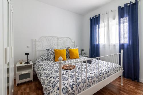 Una cama blanca con almohadas amarillas en un dormitorio en Flatguest La Herradura, en Telde