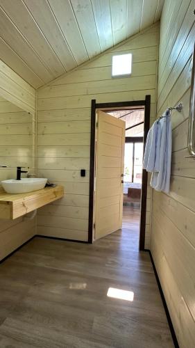 a bathroom with a sink in a wooden cabin at Гостинично-банный комплекс PARADISE in Shchūchīnsk