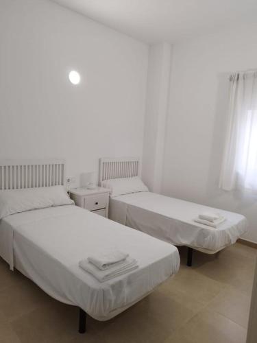 two beds in a room with white walls at La Casita del pescador in Cabo de Palos