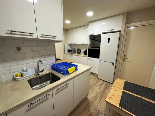 uma cozinha com armários brancos, um lavatório e um frigorífico em Rooms Sepulveda em Barcelona